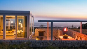 A modern house with a glass-enclosed living area and a stone patio with outdoor seating. - Amazing home in Ragusa (Ragusa)