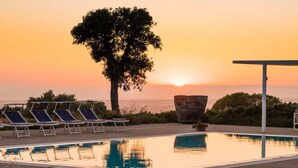 A pool with lounge chairs and a large tree, set against a sunset backdrop. - Amazing home in Ragusa (Ragusa)