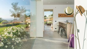 A modern kitchen with a bar area, a large window with a view of the countryside, and a dining area with bar stools. - Amazing home in Ragusa (Ragusa)