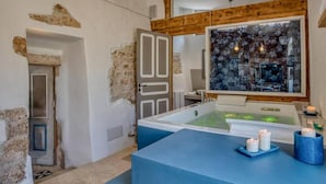 A spa room with a bathtub, candles, and a view of a forest through a window. - Villa 'Trulli Life' with Private Pool, Wi-Fi and Air Conditioning (Putignano)
