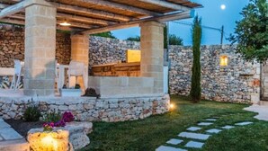 A stone-built outdoor seating area with a pergola, stone walls, and a stone pathway. - Villa 'Trulli Life' with Private Pool, Wi-Fi and Air Conditioning (Putignano)