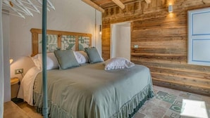 A wooden-paneled room with a bed, a nightstand, and a wall-mounted light fixture. - Villa 'Trulli Life' with Private Pool, Wi-Fi and Air Conditioning (Putignano)
