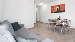 A living room with a grey sofa, a dining table with chairs, and a wall-mounted painting of a Buddha statue. - Holiday Home "Casa Lierna" with Private Terrace, Balcony and Wi-Fi (Lierna)
