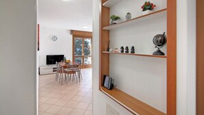 A modern living room with a dining area, wooden shelves, and a TV. - Holiday Home "Casa Lierna" with Private Terrace, Balcony and Wi-Fi (Lierna)
