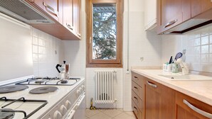 A kitchen with wooden cabinets, a stove, a window, and a tiled backsplash. - Holiday Home "Casa Lierna" with Private Terrace, Balcony and Wi-Fi (Lierna)