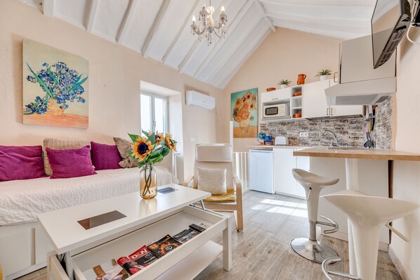 A modern living room with a sofa, a coffee table, a chair, and a kitchen area with a microwave and a sink.