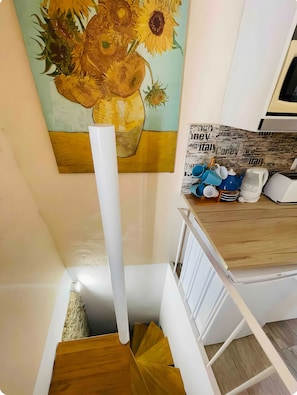 Une cuisine avec un tableau représentant des tournesols, un meuble blanc et un plan de travail en bois.
