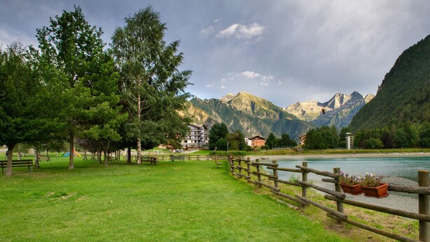 Un parque con vallas de madera, mesas de picnic y bancos.