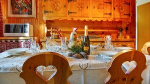 Una mesa de comedor dispuesta con cristalería, una botella de champán y un centro de mesa decorativo.