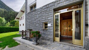 Un edificio de piedra con puerta de madera, un letrero con el número 74 y una maceta con flores.