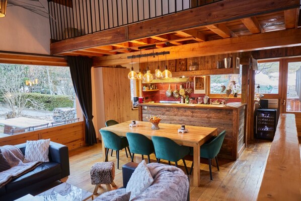 A cozy cabin-style interior with a wooden dining area, a bar, and a living space with a sofa and a coffee table.