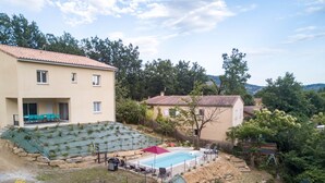 A residential area with a swimming pool, outdoor seating, and a house with a tiled roof. - Villa 'Gite Les Bouches Rouges' with Mountain View, Wi-Fi and Air Conditioning (Vesseaux)