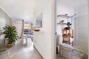 Un bagno moderno con doccia, servizi igienici e mensole con piante e asciugamani.