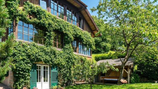 Ein zweistöckiges Gebäude mit Holzfassade, großen Fenstern und einer grünen Tür.