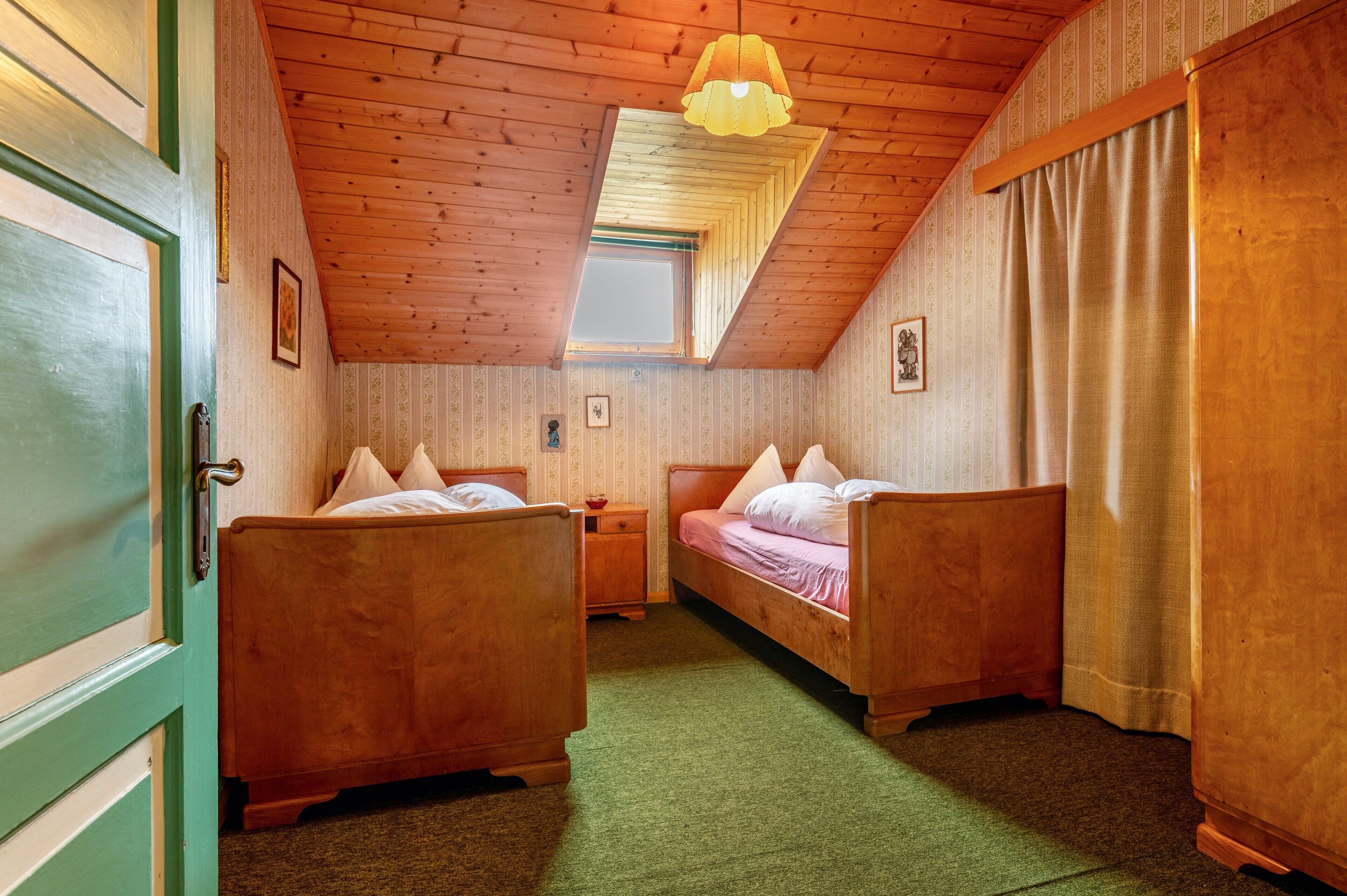 Une pièce avec deux lits en bois, une petite fenêtre et un luminaire au plafond.
