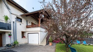 Ein zweistöckiges Haus mit Balkon, Garage und Baum im Garten.