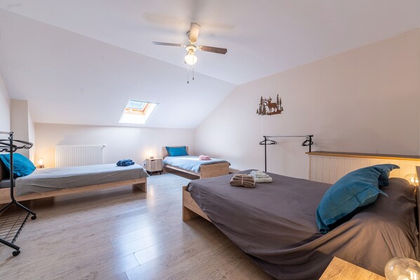 Une chambre de type dortoir avec deux lits, un ventilateur de plafond, un puits de lumière et un radiateur.