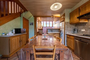 Une cuisine avec des meubles en bois, un lave-vaisselle en acier inoxydable et une table à manger recouverte de plastique.