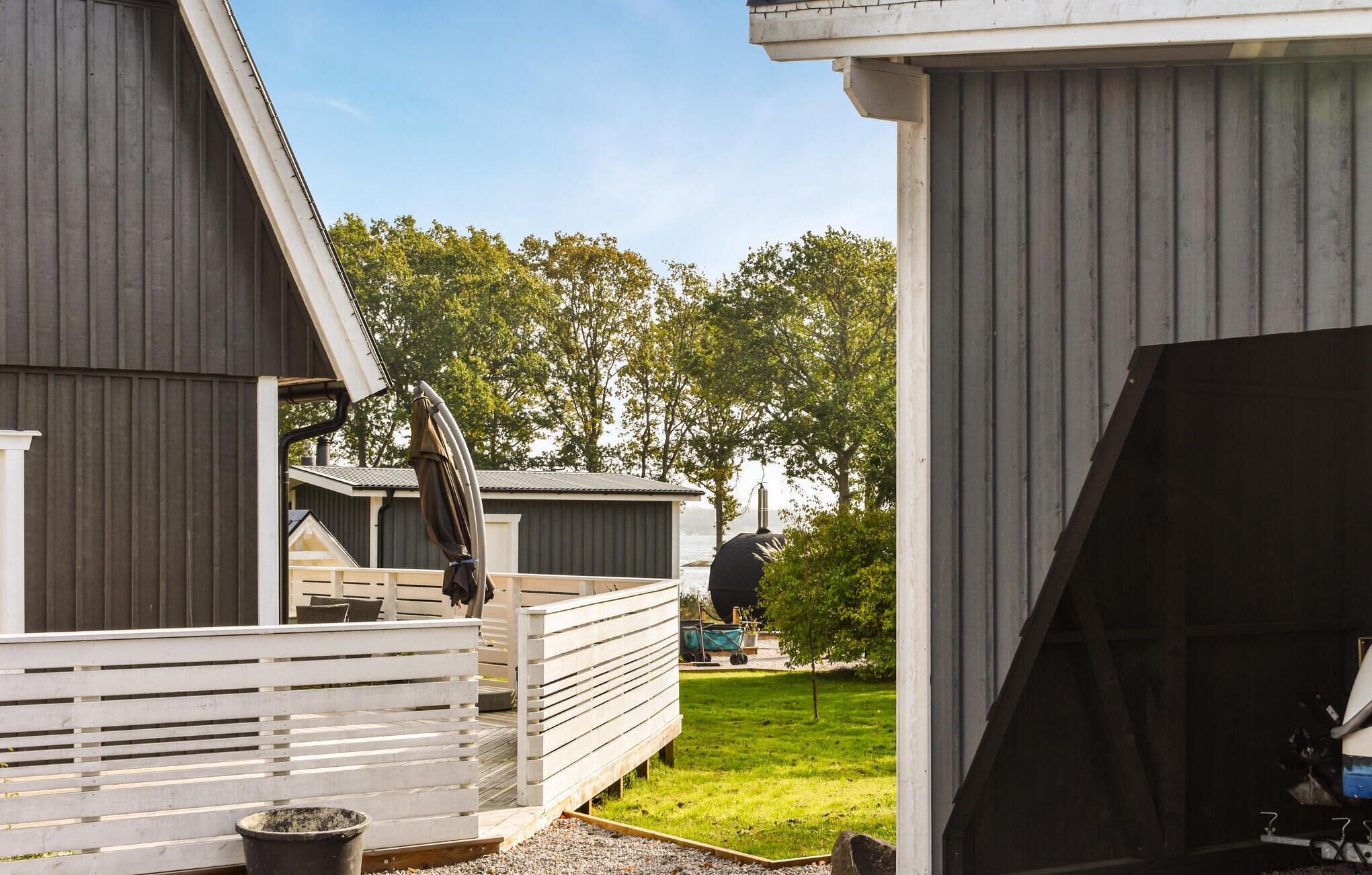 Un espace extérieur abrité doté d’une terrasse en bois, d’un barbecue et d’un petit abri de jardin.
