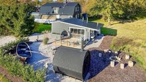 A modern house with a large deck, a boat, and a covered outdoor area.