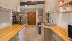 A compact kitchen with wooden countertops, a built-in sink, and a stone wall.