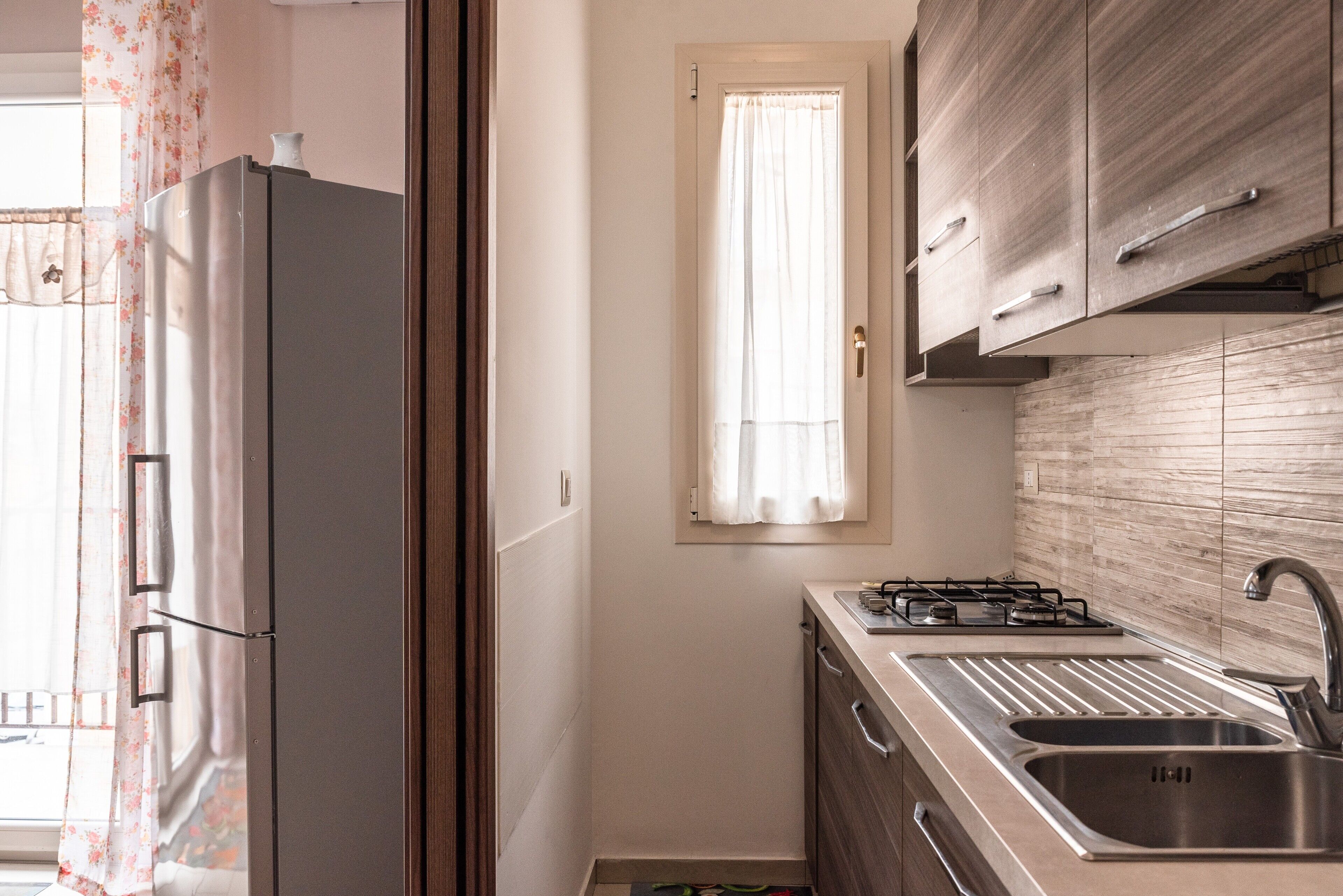 A compact kitchen with a refrigerator, a gas stove, and a sink.