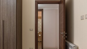 Un corridoio con una porta in legno, un termosifone e un pavimento piastrellato.