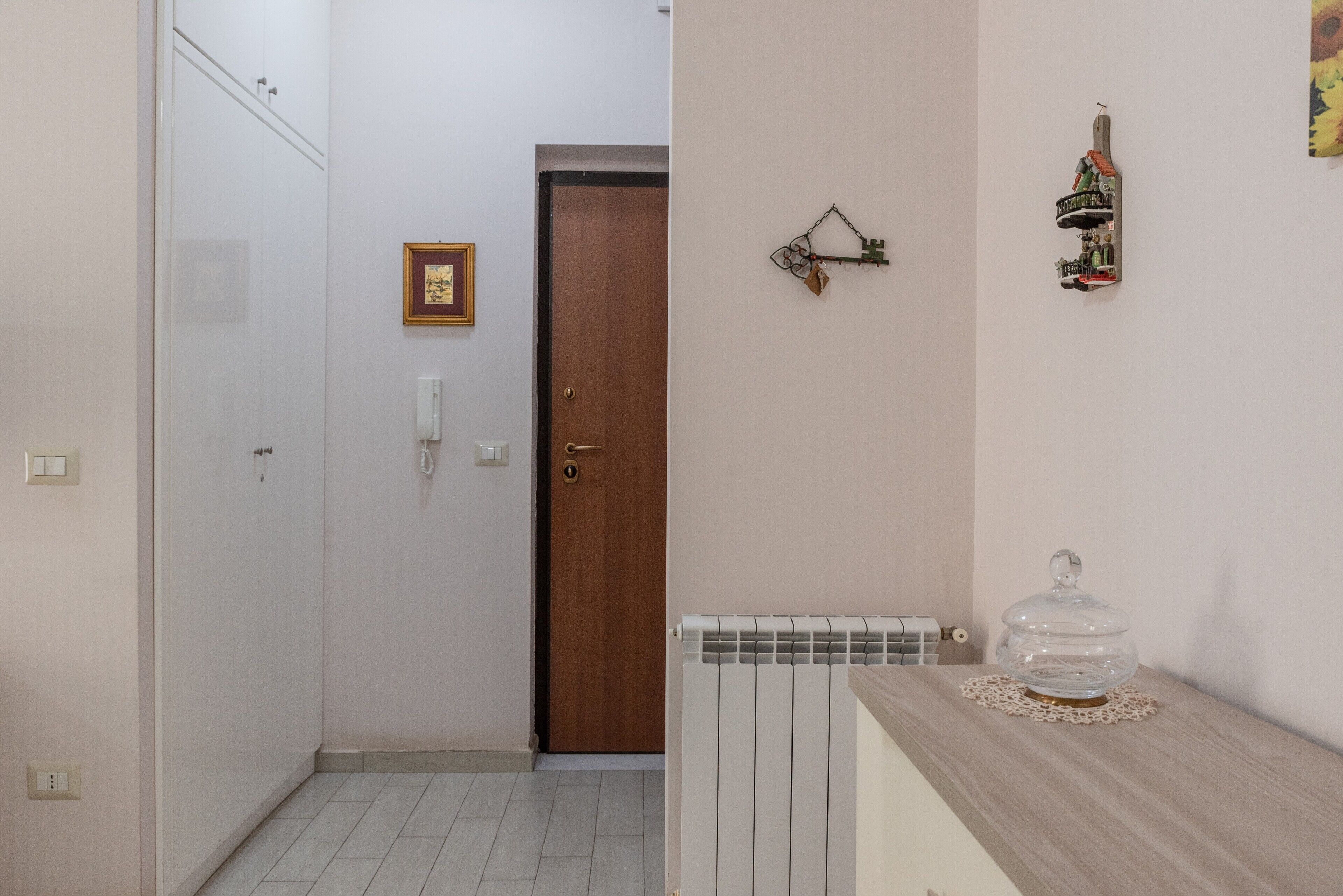 A hallway with a wooden door, a radiator, and a shelf with a decorative item.
