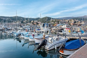 Un port de plaisance avec des bateaux amarrés, une vue sur le front de mer et des bâtiments en arrière-plan.