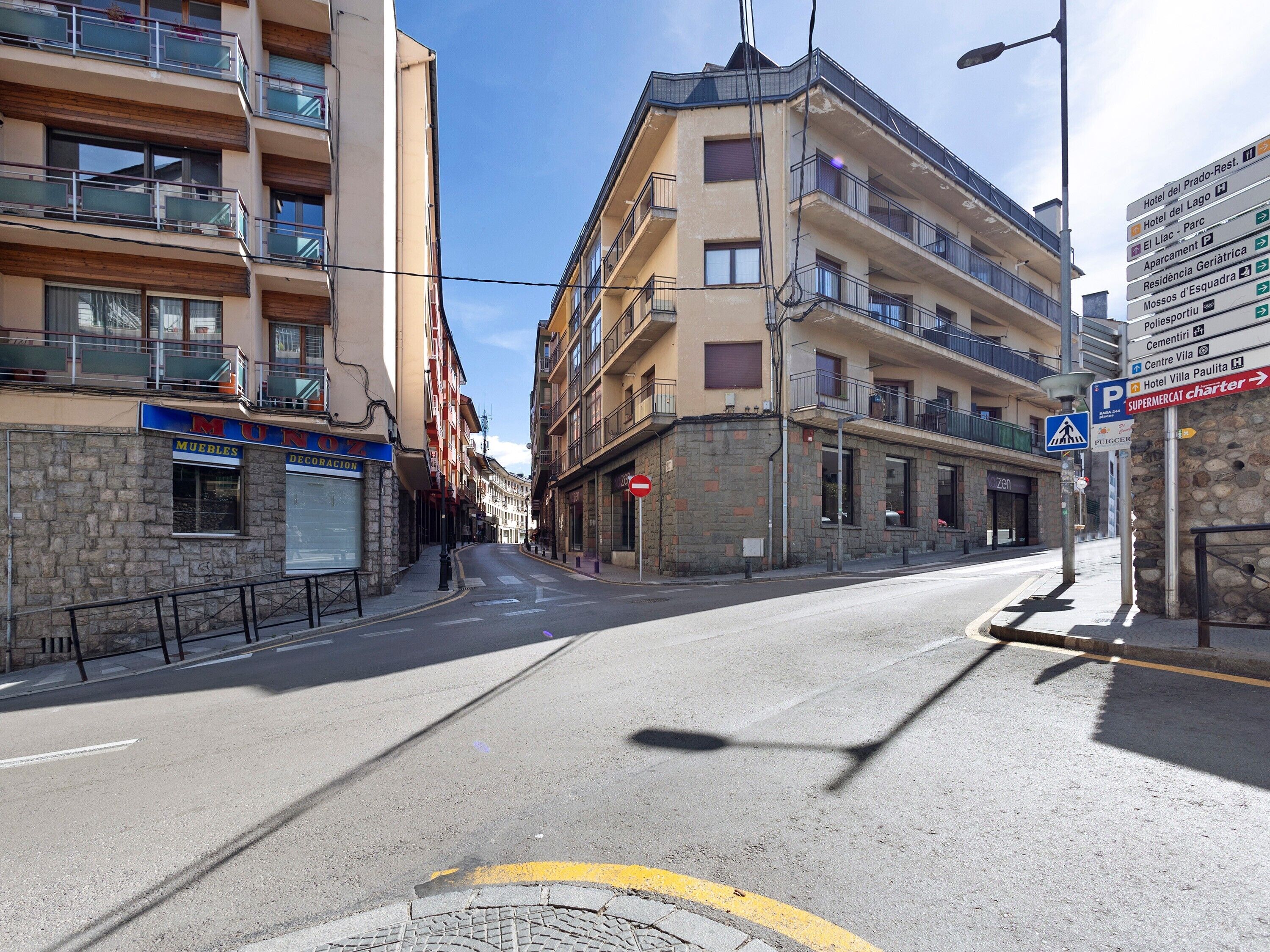 A street with multi-story buildings, a pedestrian crossing, and directional signs.