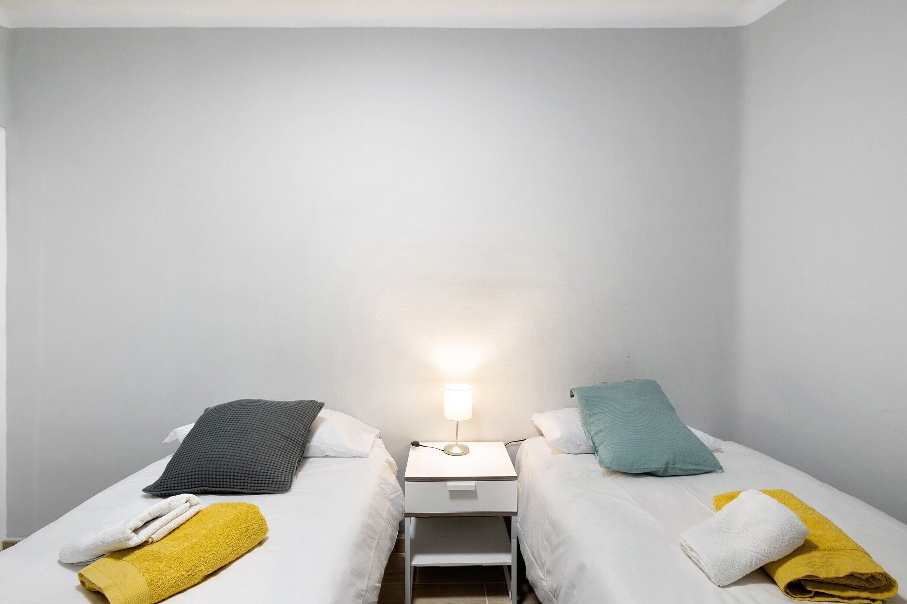 Ein Doppelzimmer mit zwei Betten, einem Nachttisch und einer Lampe.