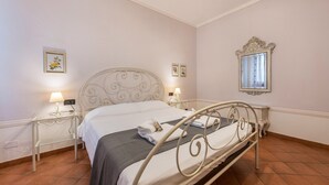 Un lit bien fait, avec un cadre en métal, deux tables de chevet avec des lampes et un miroir fixé au mur.