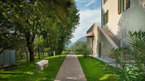 A paved pathway leading to a building with a sloped roof and a small porch. - Oleadei - Eolo Apartment with Mountain View, Wi-Fi, and Air Conditioning (San Felice del Benaco)