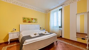 Ein Hotelzimmer mit Bett, Nachttisch, Spiegel und einem Fenster mit Vorhängen.