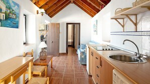 A kitchen with a wooden ceiling, a sink, and a dining area with chairs and a table. - Casa Silla Vieja Uno, private terrace and balcony in Vejer de la Frontera (Vejer de la Frontera)