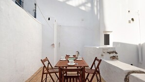 A white-walled room with a wooden table set for two, a window, and a small door. - Casa Silla Vieja Uno, private terrace and balcony in Vejer de la Frontera (Vejer de la Frontera)