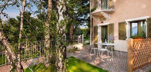 Une cour avec une table et des chaises, une clôture en bois et un bâtiment doté d’un balcon.