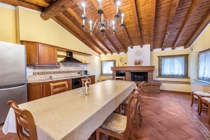 Une cuisine avec des meubles en bois, un grand îlot central, un four encastré et un lustre.