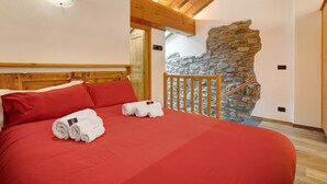 A bedroom with a wooden headboard, a stone wall, and a wooden staircase. - Studio 'Aux Pieds Du Malatra' 1 with Mountain View (Saint Rhemy en Bosses)