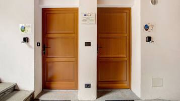 L’entrée d’un hôtel, avec deux portes en bois, un paillasson et une petite pancarte accrochée au mur.