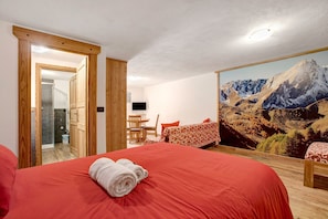 Habitación de hotel con una cama grande, un escritorio, una silla y un cuadro con vistas a la montaña.