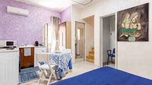 Une chambre comprenant un lit, un bureau avec une chaise, un four à micro-ondes, un évier et un espace douche.