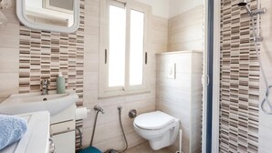 Une salle de bain avec un lavabo, des toilettes, une douche et une fenêtre.