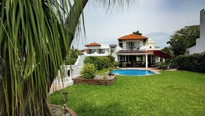 A large house with a swimming pool, a covered patio, and a well-maintained lawn. - La Puntilla, Luxury 3-bedroom, 3-bath home with heated pool in gated community (La Cruz de Huanacaxtle)