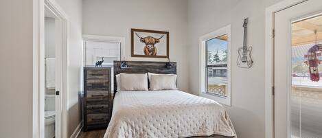 Un dormitorio con cama de madera, ventilador de techo, una obra de arte enmarcada de un toro y una guitarra en la pared.
