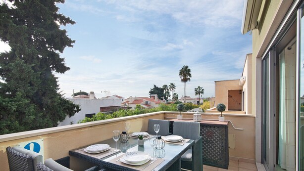 A rooftop terrace with a table set for dining, outdoor seating, and a view of the cityscape. - Apartment 'Condomínio Quinta Do Vale' with Shared Pool, Wi-Fi and Air Conditioning (Guia)