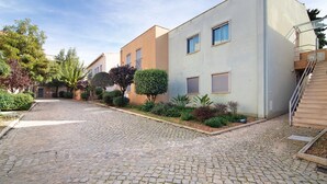A residential street with cobblestone pavement, modern two-story houses, and well-maintained landscaping. - Apartment 'Condomínio Quinta Do Vale' with Shared Pool, Wi-Fi and Air Conditioning (Guia)