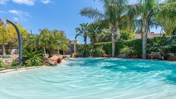 A clear swimming pool surrounded by tropical plants and a stone wall. - Villa 'Joel' with Sea View, Wi-Fi and Air Conditioning (Fontane Bianche)