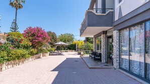 A building with a balcony, outdoor seating, and a paved walkway. - Villa 'Joel' with Sea View, Wi-Fi and Air Conditioning (Fontane Bianche)