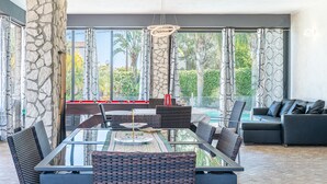 A modern dining area with a glass table, wicker chairs, and a pool in the background. - Villa 'Joel' with Sea View, Wi-Fi and Air Conditioning (Fontane Bianche)